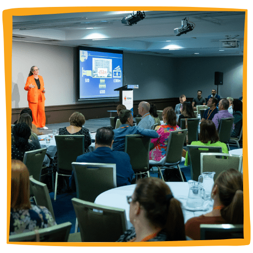 A woman in an orange suit is giving a presentation.